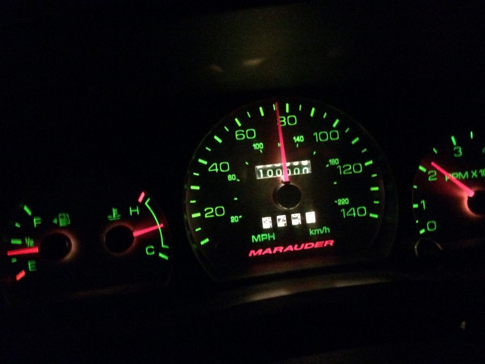Speedometer and fuel gauge illuminated green, showing 100,000 miles and 80 MPH