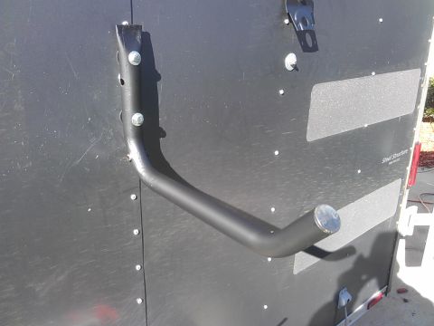 1994 Ford Bronco - A black metal ladder rack bracket is bolted to the side of a dark gray trailer.