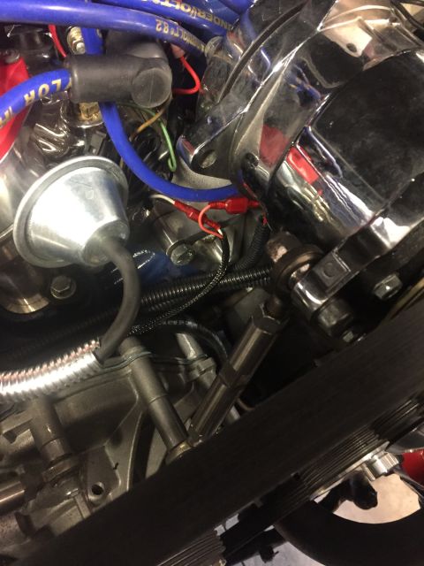 1982 Ford Bronco - A close-up view of the engine bay of a 1982 Ford Bronco, showing various chrome-finished components, blue spark plug wires, and a black ser…