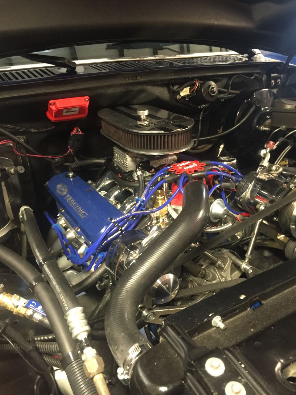 Modified V8 engine with blue valve cover and chrome air cleaner.