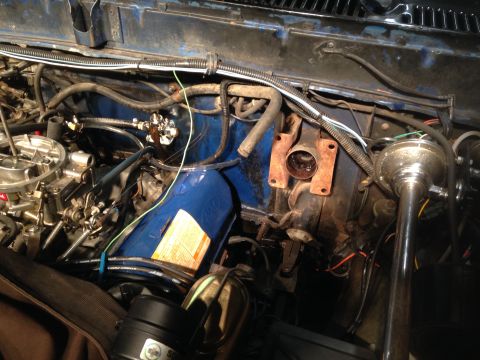 1979 Ford Bronco - A close-up view of the engine bay of a vintage Ford Bronco, showing the carburetor, fuel lines, and various hoses and wiring.