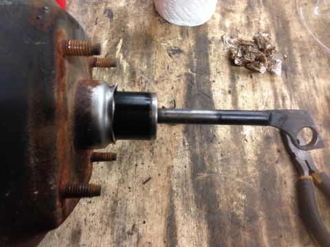 1979 Ford Bronco - A close-up view shows a rusty brake booster with a pushrod assembly attached. A pair of pliers is visible on the right side of the frame, r…