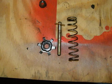 1979 Ford Bronco - Vehicle parts including a gear, pin, and springs are displayed on a wooden surface.