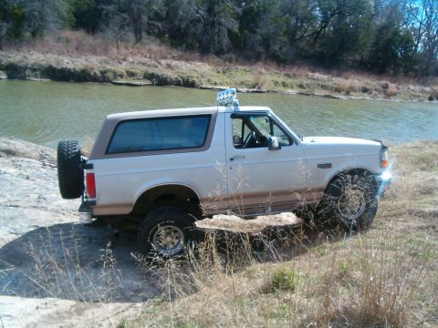 1996 Ford Bronco - 1996 Ford Bronco navigating rough terrain next to a body of water.