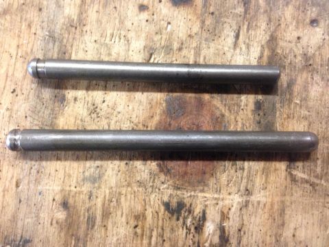 1979 Ford Bronco - Two metal rods are laid out on a wooden surface, possibly for a vehicle repair or modification.