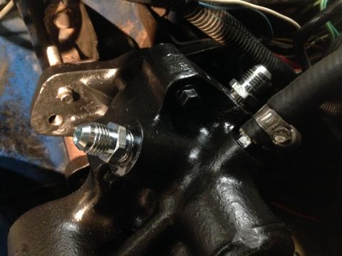 1979 Ford Bronco - Close-up view of a hydroboost conversion part, silver fittings and a hose clamp, with visible wiring and engine components in the backgroun…