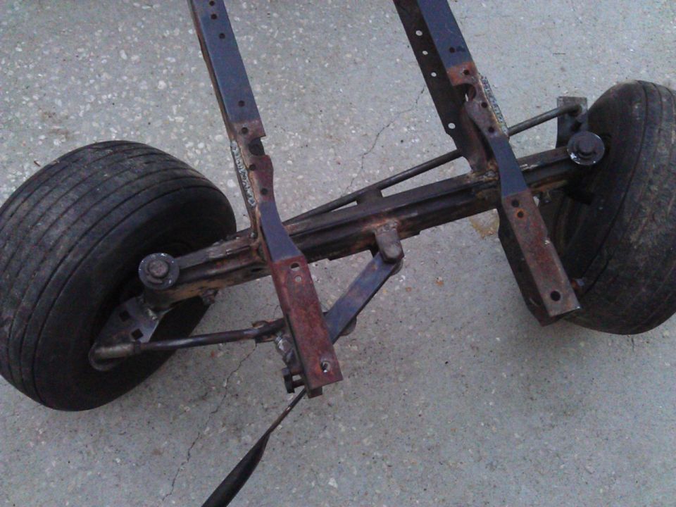 Rusty metal chassis with two tires on a concrete surface