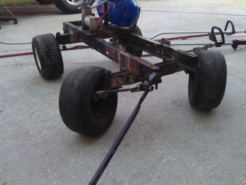 Rusted chassis with four wheels, blue tank, and air compressor