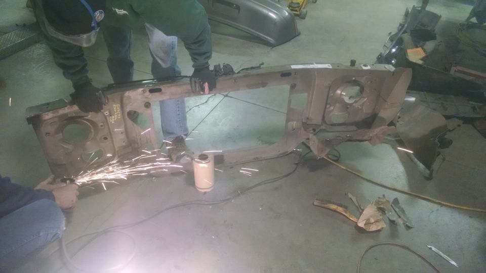 Front end frame assembly being cut with grinder, sparks flying