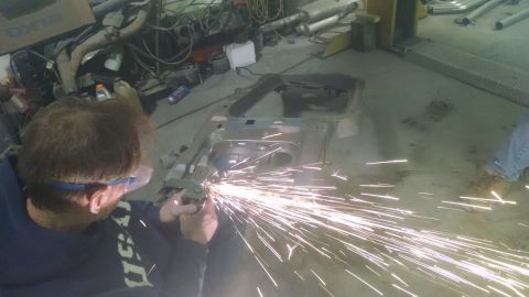 2000 Chevrolet Astro - A person works on a vehicle frame in a workshop, sparks flying from an angle grinder.
