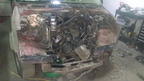 2000 Chevrolet Astro - The engine bay of a red van is visible, with the engine, wires, and hoses exposed.