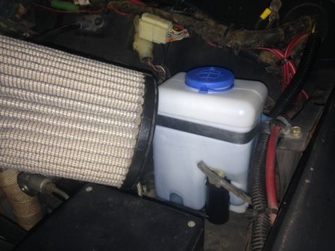 1987 Suzuki Samurai - Close-up view of engine bay components including an aftermarket air filter and a white fluid reservoir.