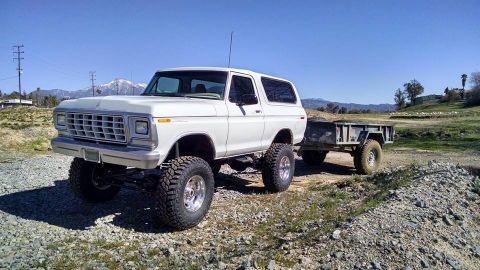 1979 Ford Bronco - A modified Ford Bronco is shown towing a trailer on a sunny day in a rural, mountainous area.