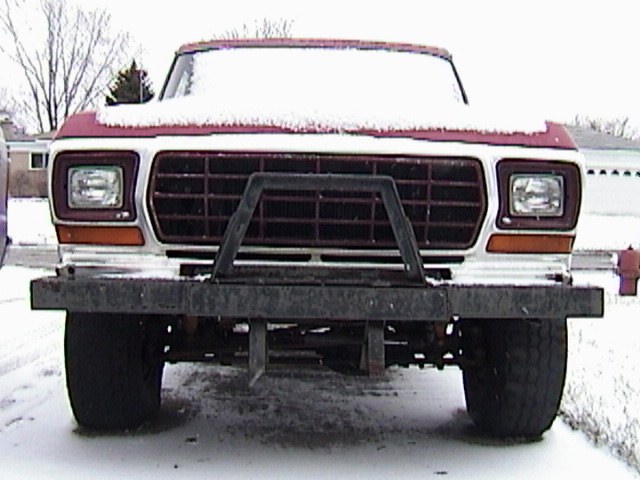 Red and white 1970s Ford 4x4 front view in snow with a flat plow-mount bumper