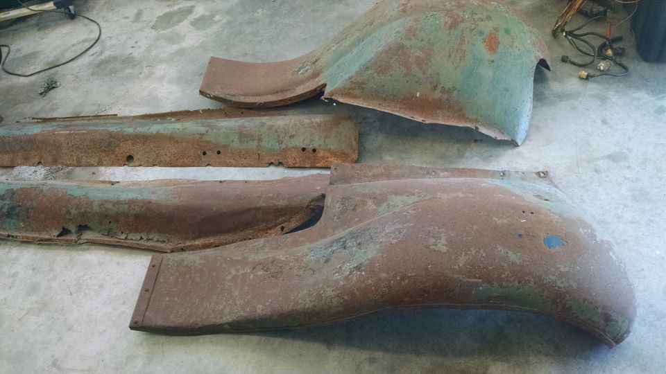 Rusted green and brown vehicle body panels on concrete floor