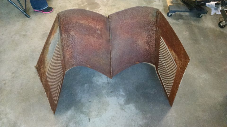 Rusty metal car part with louvers on a concrete floor