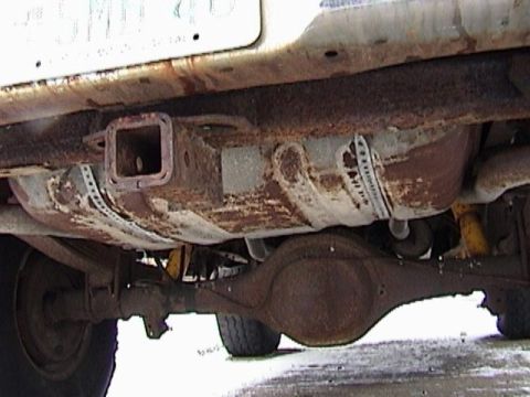 1995 Ford Bronco - Undercarriage view of a heavily rusted vehicle, showing the rear axle and trailer hitch.