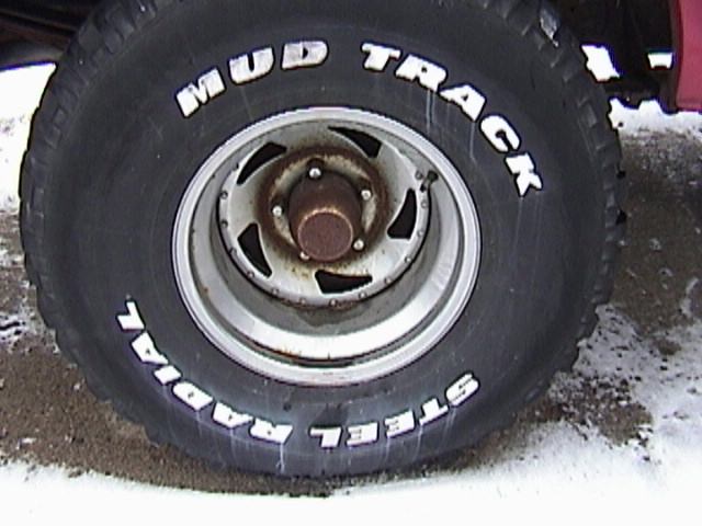 Close-up of a "Mud Track Steel Radial" tire on a vehicle wheel