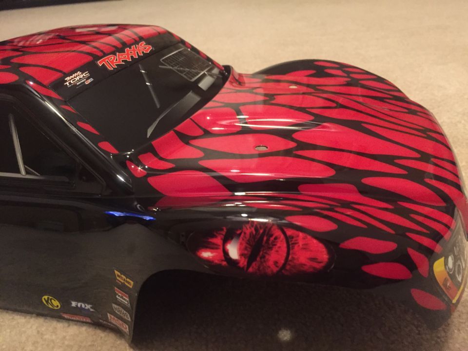 Black RC car body with red flame graphics and a red eye decal.