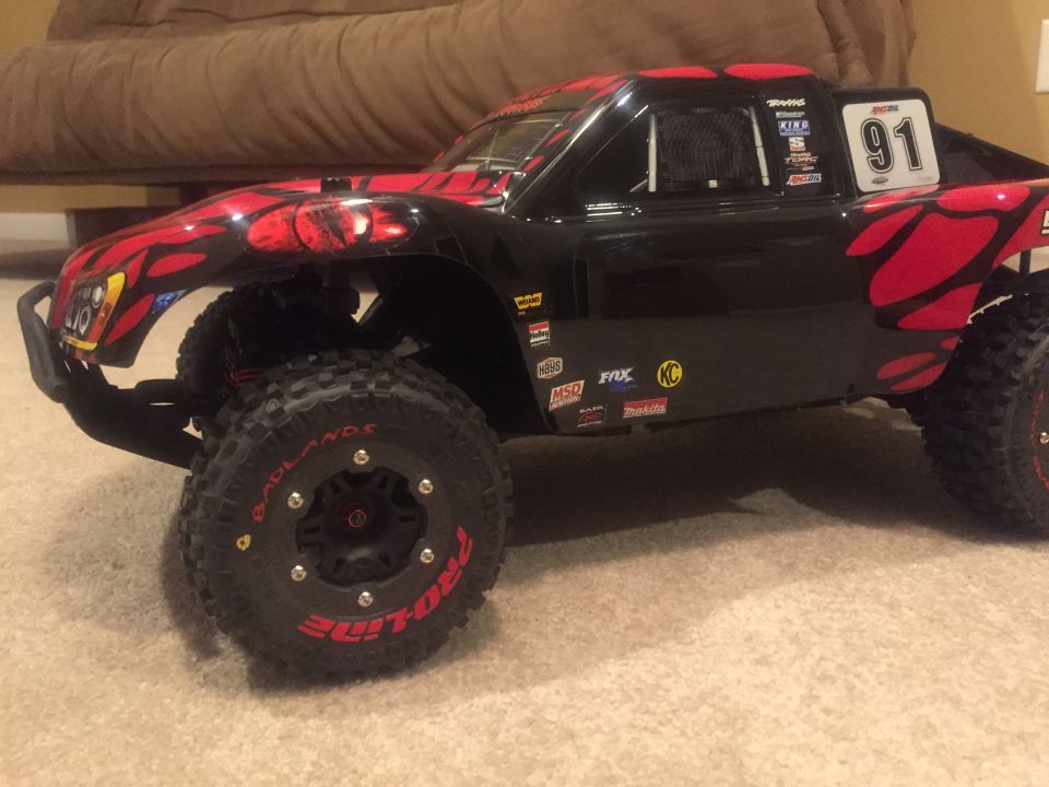 Black remote control monster truck with red flame graphics and large off-road tires.