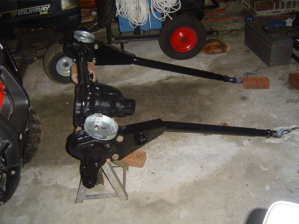 Two black differential assemblies with axles on a concrete floor.