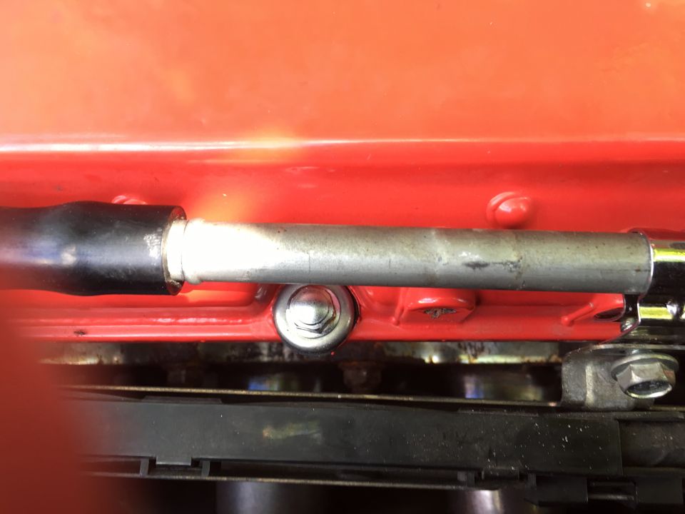 Close-up of a metal rod with black grip secured to a red surface, with a black belt below.