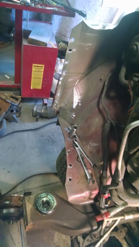 2000 Chevrolet Astro - A close-up view of the fender well area of a vehicle, showing exposed metal with drilled holes and some tools. The vehicle appears to be un…