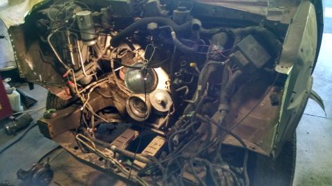 2000 Chevrolet Astro - The engine bay of a Chevrolet Astro van is shown with the hood removed, revealing the engine, wiring, and various components. A work light…