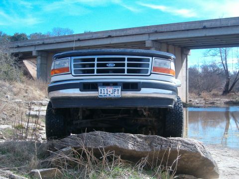 1996 Ford Bronco - This Ford F-250 truck is positioned on rocks with a river and bridge in the background.
