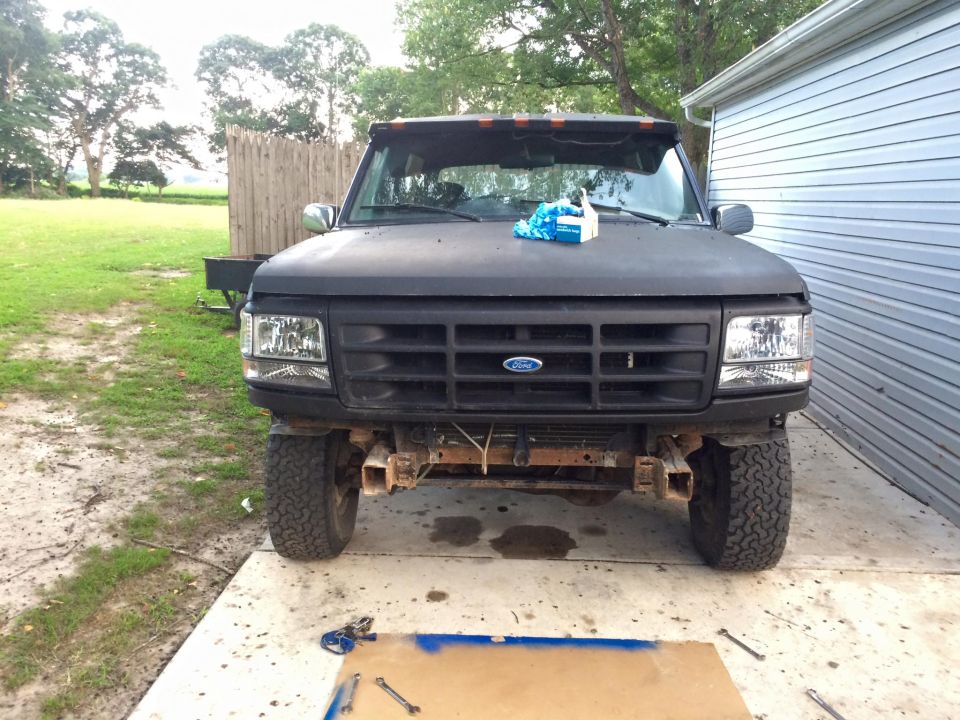 Front view of a dark Ford Bronco with tools on the ground.