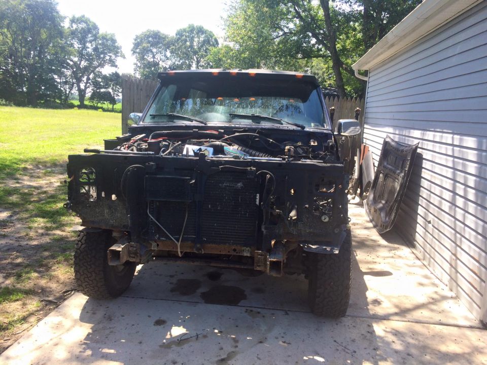 1994 Ford Bronco with front end removed, parked next to a building.