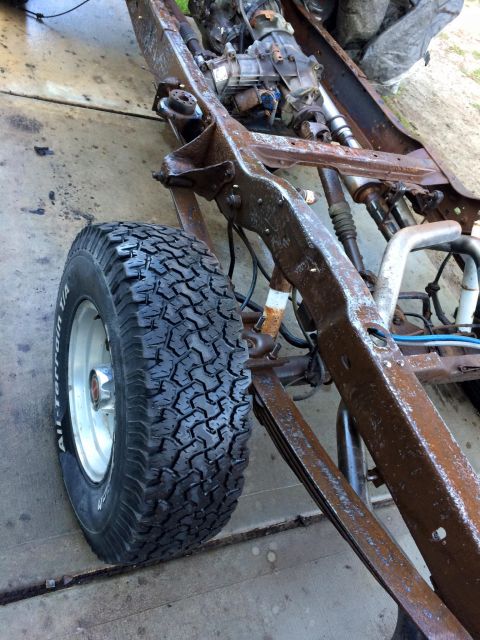 1994 Ford Bronco - The heavily rusted frame and suspension of a 1994 Ford Bronco is shown from a low-angle side view. A large, knobby all-terrain tire is moun…