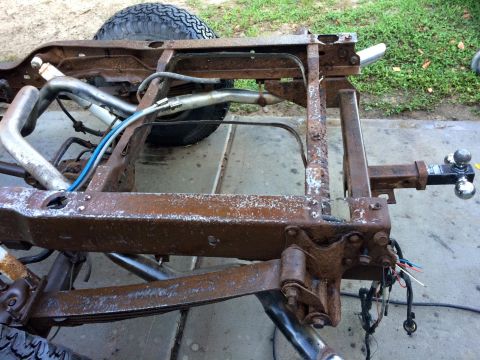 1994 Ford Bronco - The heavily rusted frame of a vehicle, likely a truck or SUV, is shown outdoors. Visible components include leaf springs, exhaust pipes, a…