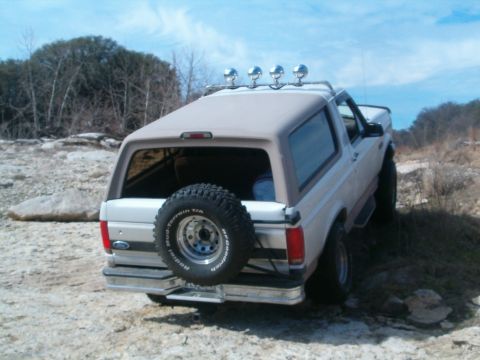 1996 Ford Bronco - This 1996 Ford Bronco is shown off-road with a spare tire on the back and roof lights.