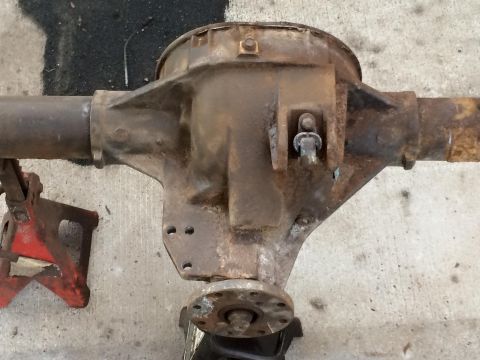 1994 Ford Bronco - A rusty rear differential assembly is shown supported by a red jack stand on a concrete surface. The assembly appears to be from a truck or…