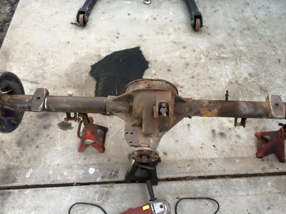 Rusty rear axle assembly with brake drum on jack stands.