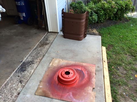 1994 Ford Bronco - A red brake drum is spray painted on a piece of cardboard on a concrete driveway. A brown metal panel, possibly a fender or body panel, is…