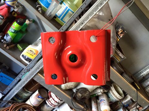 1994 Ford Bronco - A bright red, metal bracket with four circular holes is shown in the center of the frame, resting on a shelf with various automotive fluids…
