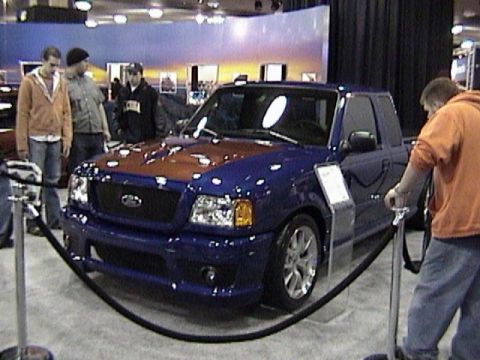 1995 Ford Bronco - A blue Ford Ranger pickup truck with an orange hood is displayed at an auto show.