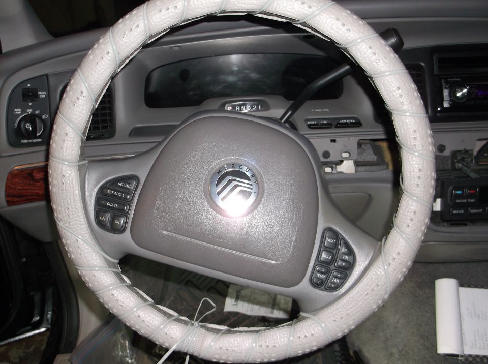 Interior of a 2001 Mercury Grand Marquis showing steering wheel with white cover and dashboard.