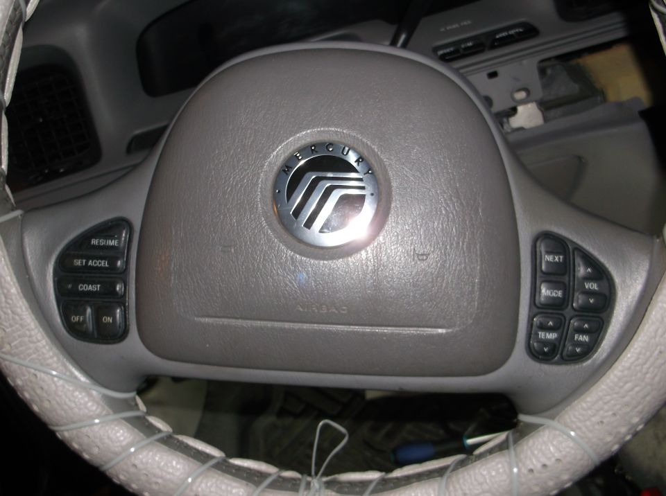 Steering wheel of a Mercury Grand Marquis with cruise control and audio/climate buttons.