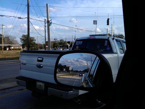 1994 Ford Bronco - A white Ford pickup truck is seen from the passenger side, reflected in the side mirror. The truck has several antennas mounted on the roof…