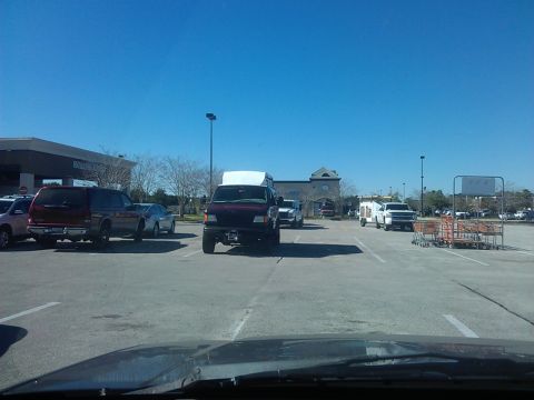 1994 Ford Bronco - A maroon Ford Econoline van with a white topper is parked in a parking lot. The van is lifted and has large tires, suggesting modifications.