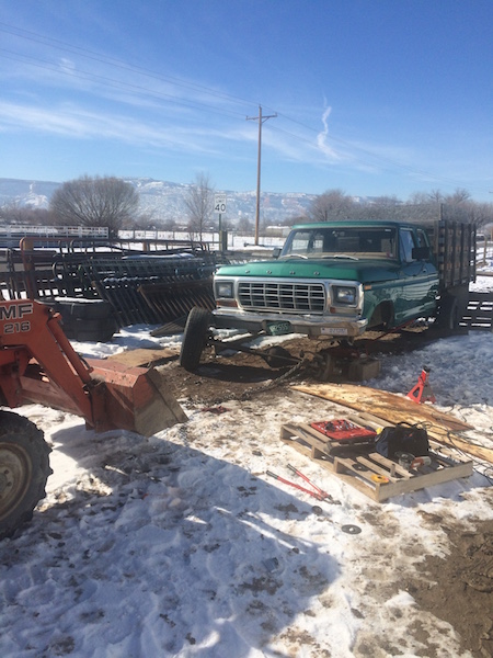 1981 Ford Bronco - A green Ford pickup truck is parked in a snowy yard with a tractor in the foreground. The truck appears to be undergoing some mechanical wo…