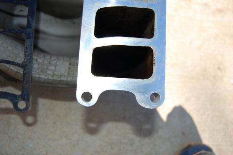 1994 Ford Bronco - A close-up of a metal intake manifold gasket with two rectangular ports and two bolt holes is shown. A black gasket with a similar shape is…
