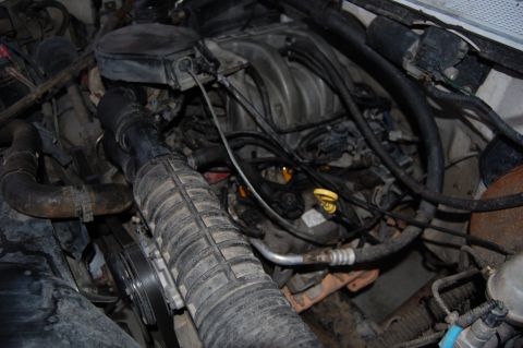 1994 Ford Bronco - A close-up view of a Ford Bronco engine bay, showing the intake manifold, air intake hose, and various hoses and wiring.