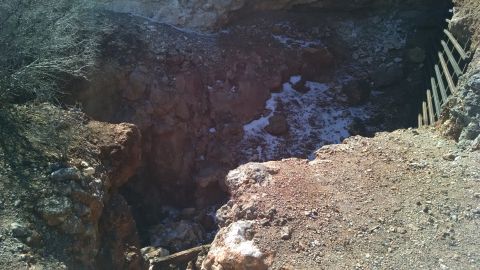 1979 Ford Bronco - A wide shot of a deep, rocky pit with some snow patches on the ground. A wooden fence-like structure is visible on the right side of the pi…