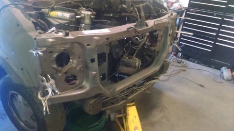 2000 Chevrolet Astro - The front end of a disassembled vehicle, likely a 2000 Chevrolet Astro van, is shown in a workshop setting. The vehicle's front clip has be…