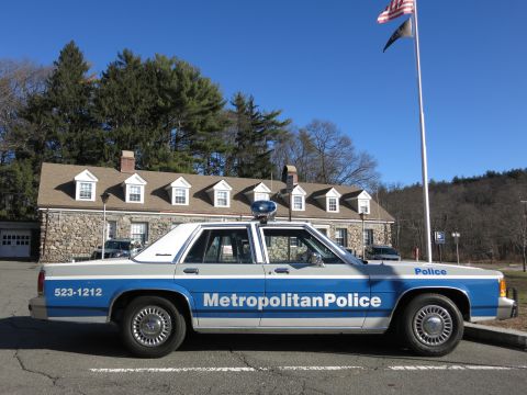 1991 Ford LTD Crown Victoria - Photo of a Metropolitan Police Crown Victoria patrol car parked outside a stone building.