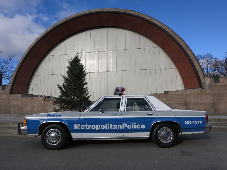 Side view of Metropolitan Police Crown Victoria in front of an arched concert shell